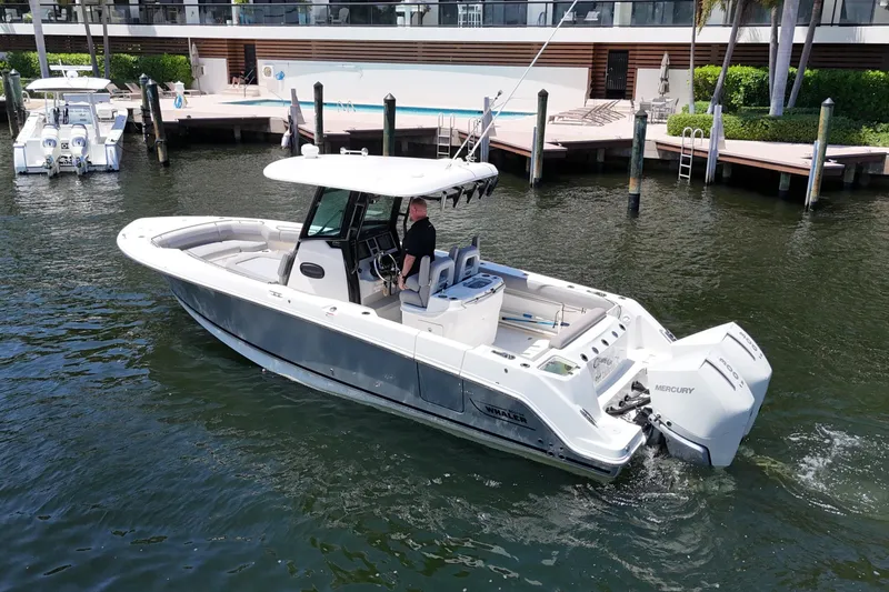 Slide: The Image of 2024 Boston Whaler 280 Outrage boat cruising near a dockside pool area. - 10