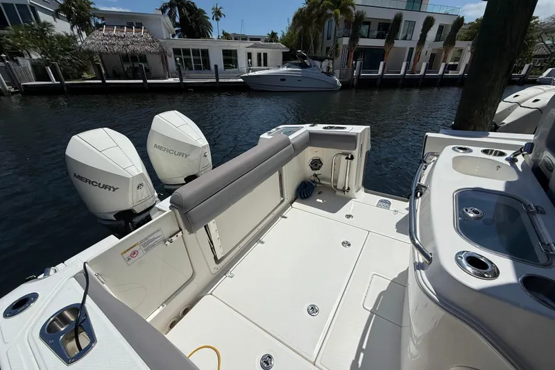 Slide: The Image of 2024 Boston Whaler 280 Outrage boat with dual Mercury engines docked by waterfront homes. - 21
