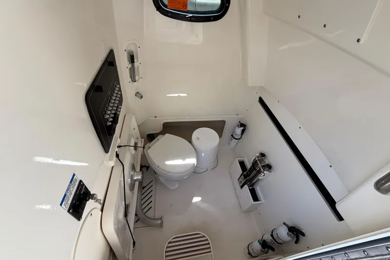 Slide: The Image of 2024 Boston Whaler 280 Outrage cabin interior with toilet and sink. - 24