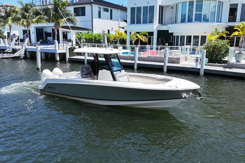 Slide: The Image of 2024 Boston Whaler 280 Outrage boat cruising near waterfront homes. - 3