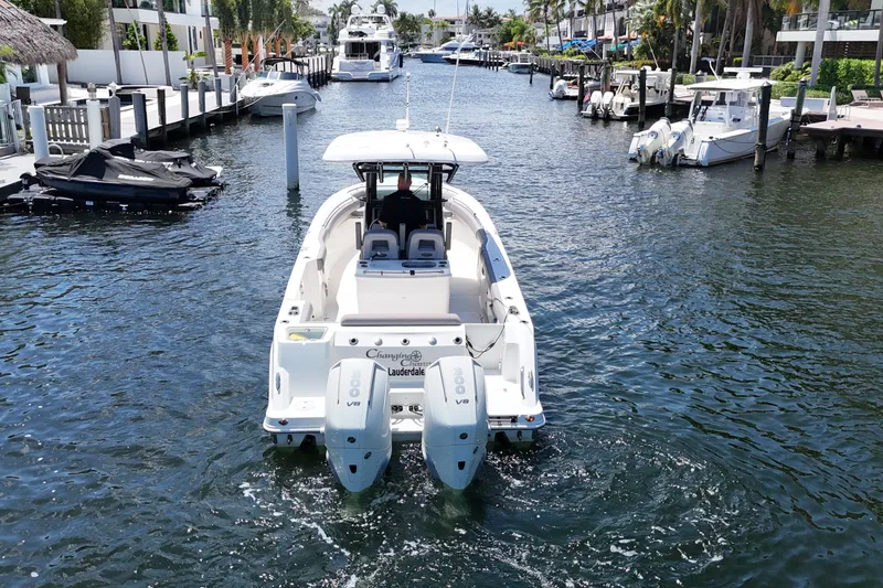 Slide: The Image of 2024 Boston Whaler 280 Outrage cruising in a scenic marina with multiple boats docked. - 9