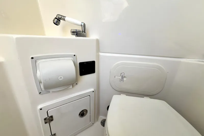 Slide: The Image of Interior of 2021 Cobia 240 Center Console boat's compact bathroom with sink and toilet. - 103