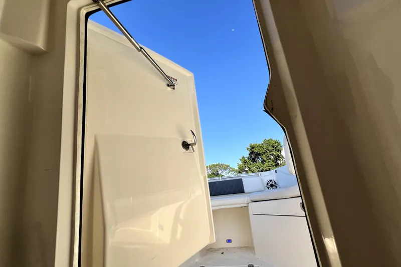 Slide: The Image of 2021 Cobia 240 Center Console boat interior with open hatch and clear blue sky. - 105