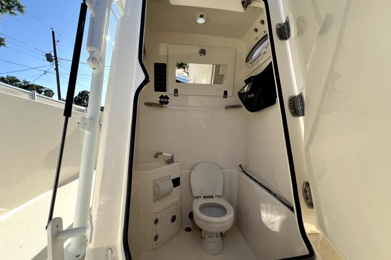 Slide: The Image of Interior of 2021 Cobia 240 Center Console boat featuring a compact marine toilet. - 107