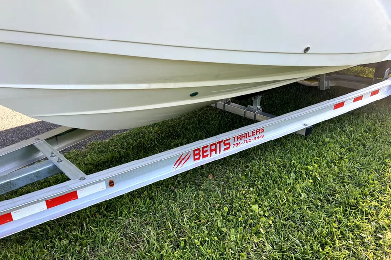 Slide: The Image of 2021 Cobia 240 Center Console boat on Beats trailer, parked on grass. - 11