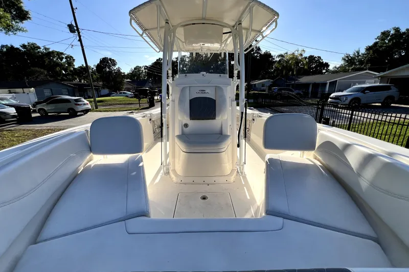 Slide: The Image of 2021 Cobia 240 Center Console boat interior with seating and console, parked in a residential area. - 116