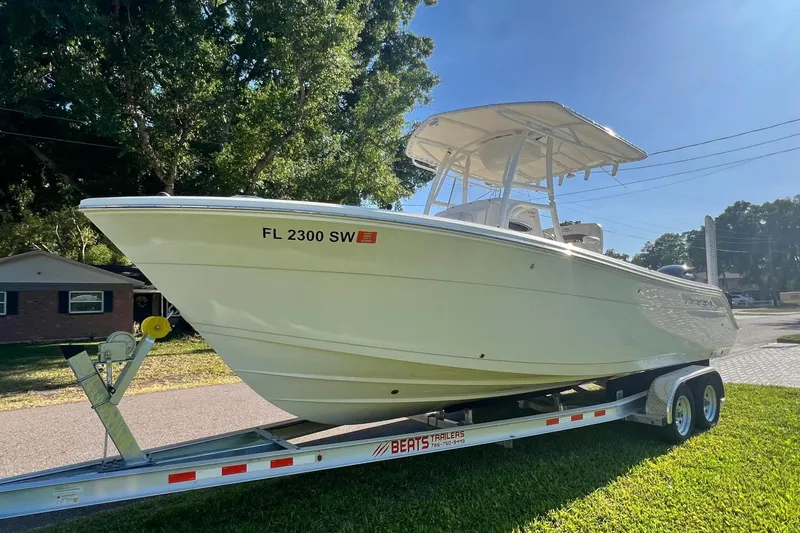 Slide: The Image of 2021 Cobia 240 Center Console boat on trailer, parked in sunny residential area. - 12