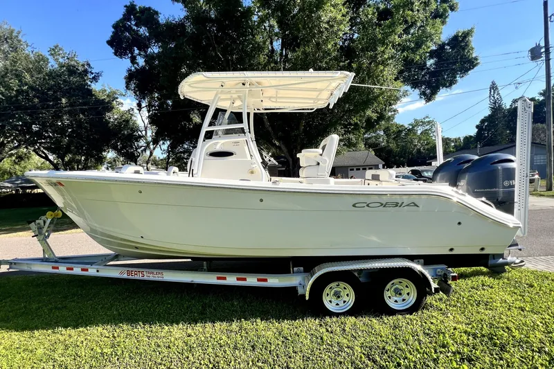 Slide: The Image of 2021 Cobia 240 Center Console boat on trailer, parked on grass, sunny day. - 13