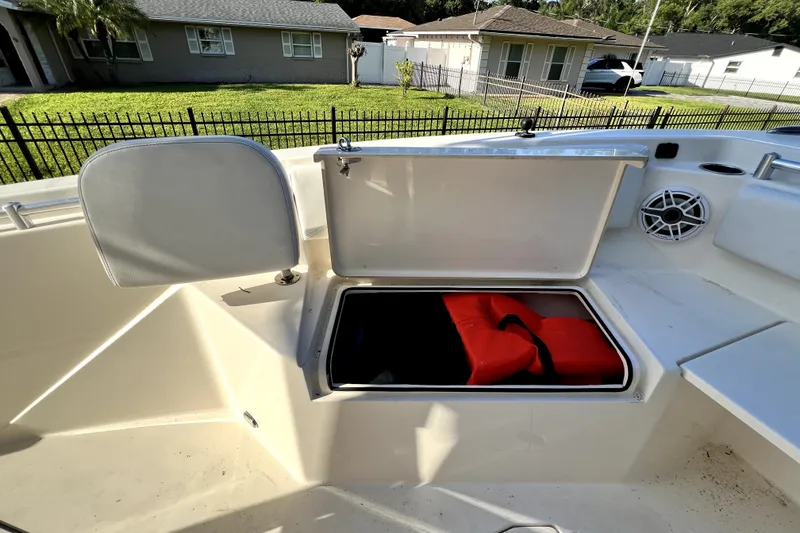 Slide: The Image of Open storage compartment on 2021 Cobia 240 Center Console boat with red life jacket inside. - 131