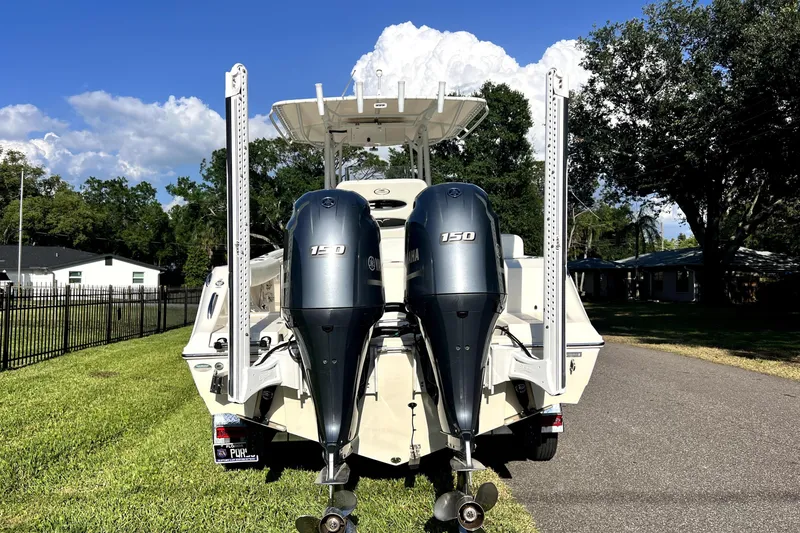 Slide: The Image of 2021 Cobia 240 Center Console boat with dual Yamaha 150 engines, parked on grass. - 15