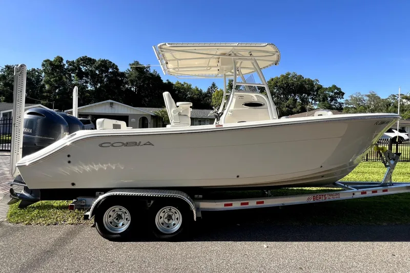 Slide: The Image of 2021 Cobia 240 Center Console boat on trailer, parked outdoors under clear blue sky. - 18