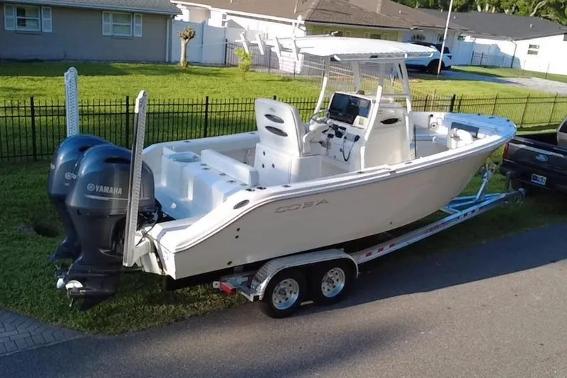 Slide: The Image of 2021 Cobia 240 Center Console boat on trailer, parked beside a house. - 2