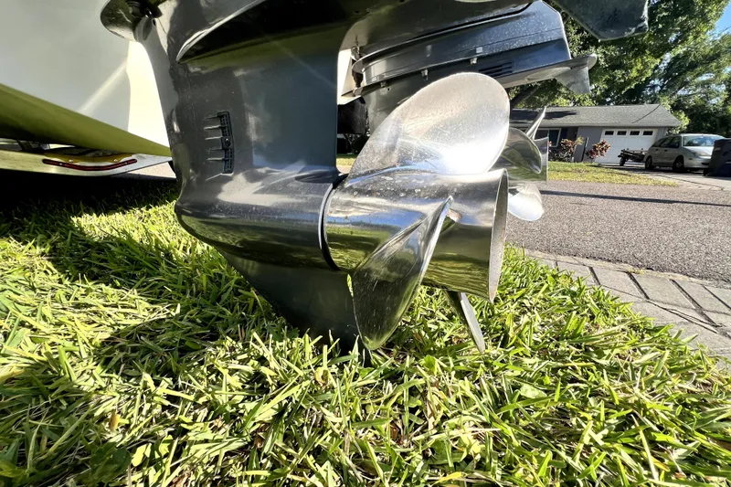 Slide: The Image of 2021 Cobia 240 Center Console boat propeller on grass, showcasing shiny metal blades. - 24