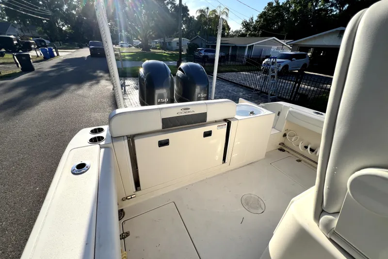 Slide: The Image of 2021 Cobia 240 Center Console boat with dual 150 engines, parked on a sunny street. - 37