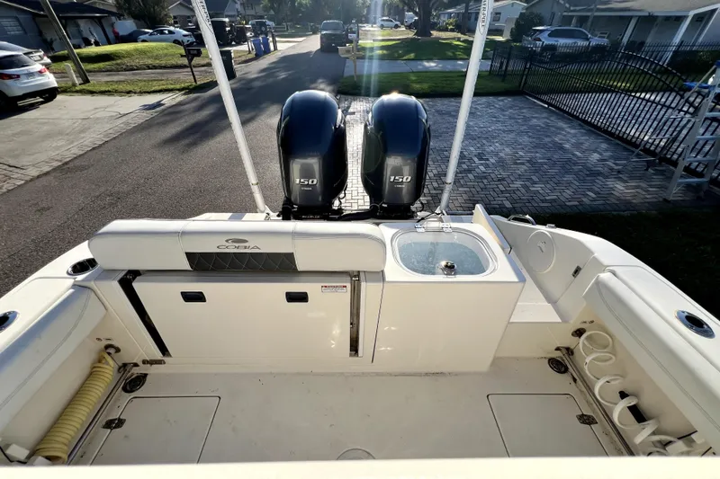 Slide: The Image of 2021 Cobia 240 Center Console boat with dual 150 engines, parked in a residential area. - 38