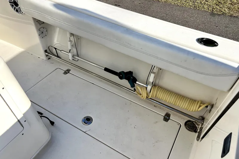 Slide: The Image of 2021 Cobia 240 Center Console boat deck with storage compartment and coiled hose. - 52