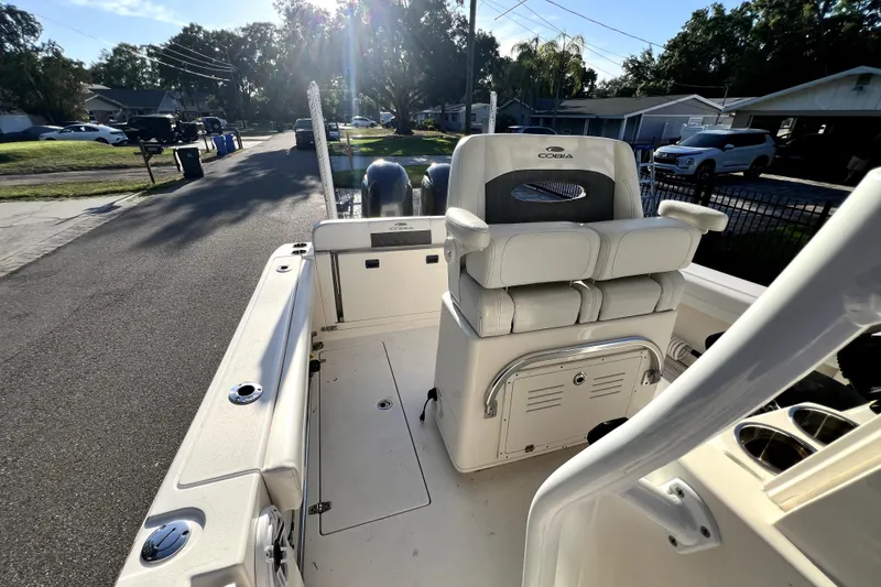Slide: The Image of 2021 Cobia 240 Center Console boat interior with seating and storage, parked in a residential area. - 62