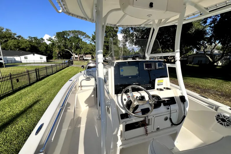 Slide: The Image of 2021 Cobia 240 Center Console boat with modern dashboard and steering, parked on grass. - 73