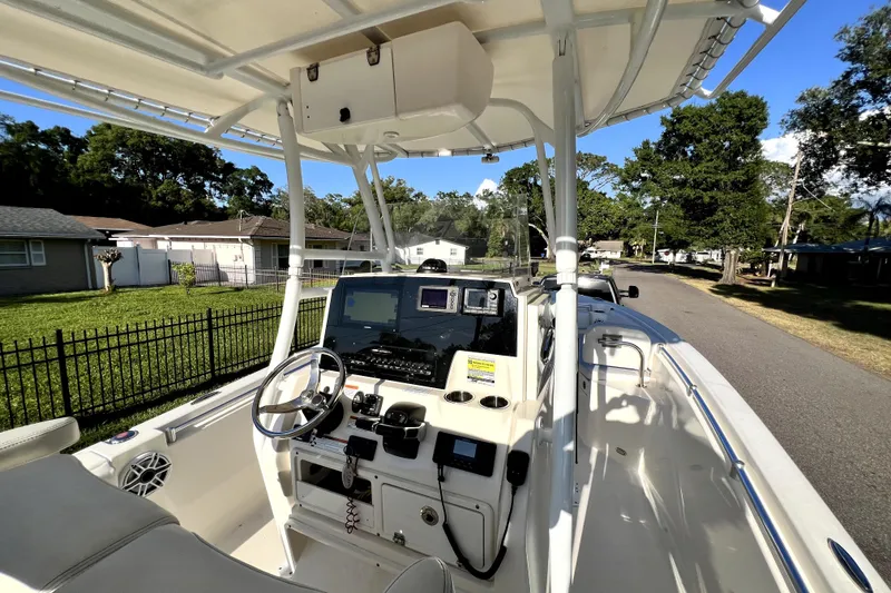 Slide: The Image of 2021 Cobia 240 Center Console boat with steering wheel and navigation equipment, parked on a residential street. - 74