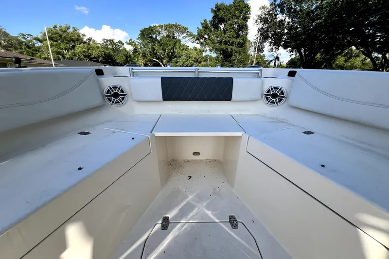Slide: The Image of 2021 Cobia 240 Center Console boat interior with seating and speakers, surrounded by trees. - 85