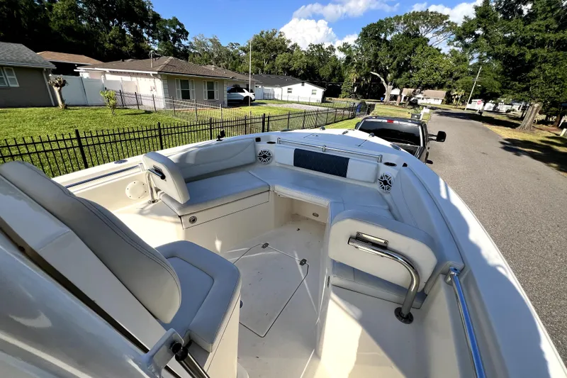 Slide: The Image of 2021 Cobia 240 Center Console boat interior with seating, parked on a residential street. - 89