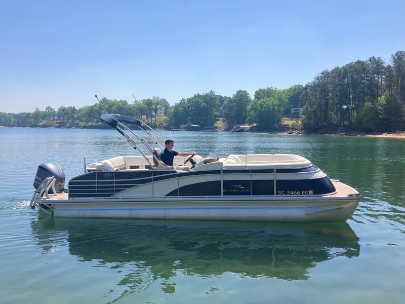 Slide: The Image of 2019 Bennington 23 QLC pontoon boat on a serene lake. - 4