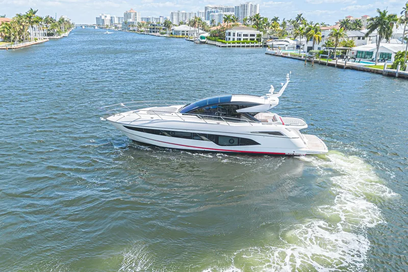 Slide: The Image of 2021 Sunseeker Predator 60 EVO yacht cruising in a scenic waterfront area. - 2