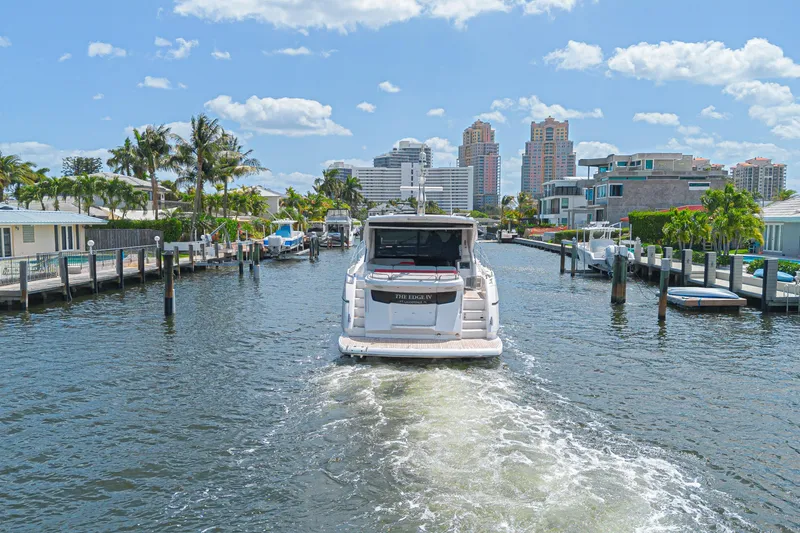 Slide: The Image of 2021 Sunseeker Predator 60 EVO yacht cruising through a scenic canal with city skyline. - 5