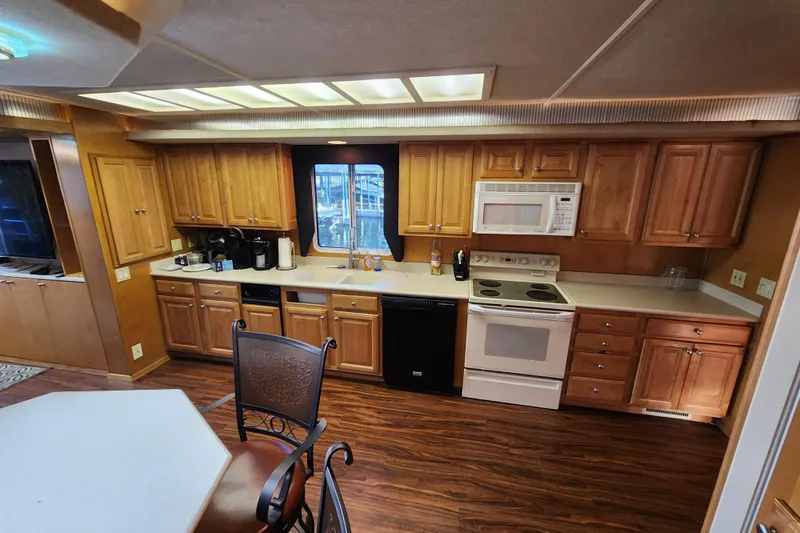 Slide: The Image of Spacious kitchen in a 2000 Sharpe 85 model houseboat with wooden cabinets and modern appliances. - 15