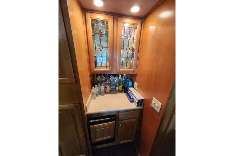 Slide: The Image of Wooden cabinet with glass doors, countertop with bottles, in a 2000 Sharpe model 85. - 17
