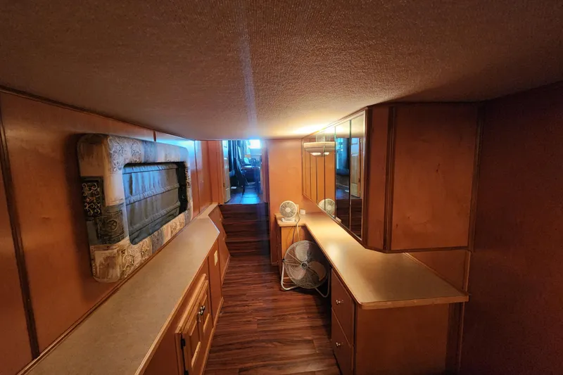 Slide: The Image of Narrow wooden interior of a 2000 Sharpe 85 houseboat with cabinets and a fan. - 21