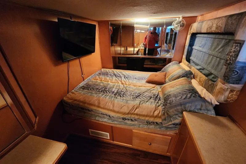 Slide: The Image of Cozy bedroom in 2000 Sharpe 85 houseboat with TV, mirrored wall, and patterned bedding. - 22