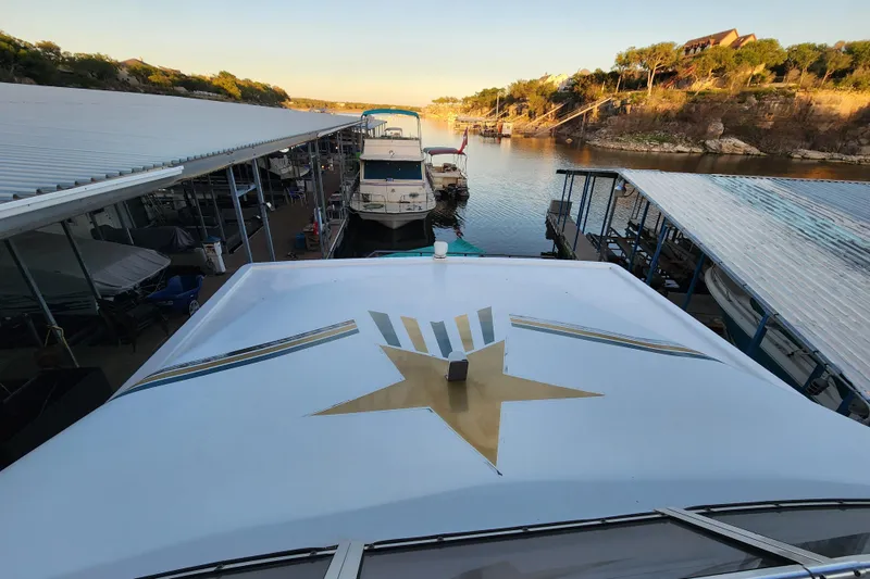 Slide: The Image of Houseboat docked at marina, featuring a star design on the roof, under a clear sky. - 37