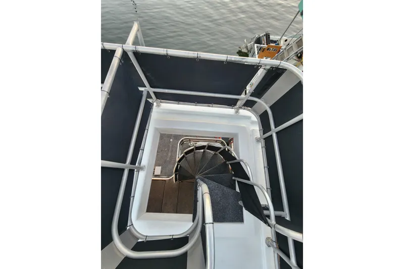 Slide: The Image of Spiral staircase on a 2000 Sharpe 85 boat, overlooking calm water. - 44