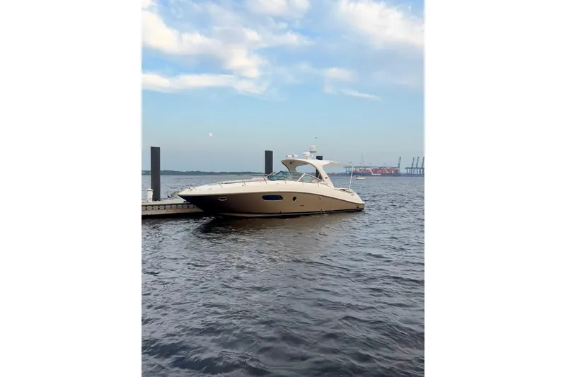 Slide: The Image of 2009 Sea Ray Sundancer 350 yacht docked on calm water under a blue sky. - 6