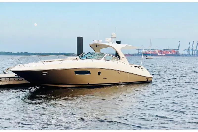 The Image of 2009 Sea Ray Sundancer 350 yacht docked on calm water with industrial background. - 2