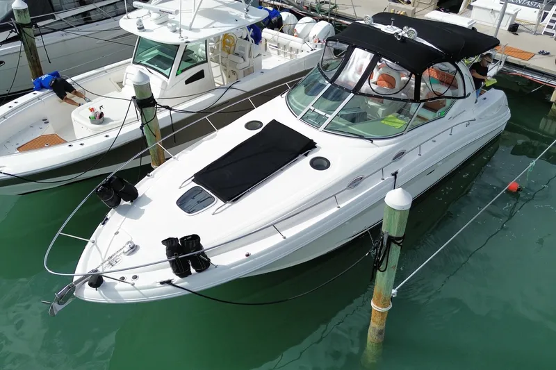 The Image of 2004 Sea Ray 340 Sundancer yacht docked in marina, featuring sleek design and black canopy. - 0