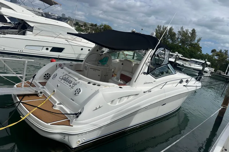 Slide: The Image of 2004 Sea Ray 340 Sundancer yacht docked at marina, featuring sleek design and black canopy. - 17
