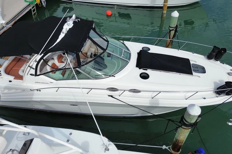 Slide: The Image of 2004 Sea Ray 340 Sundancer yacht docked in marina, featuring sleek design and black canopy. - 4