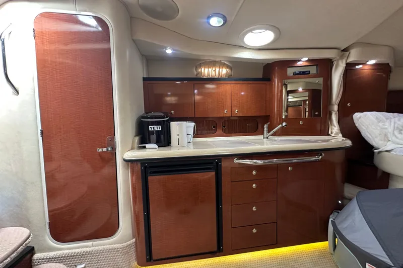 Slide: The Image of 2004 Sea Ray 340 Sundancer cabin interior with kitchenette, featuring wood cabinetry and modern appliances. - 43