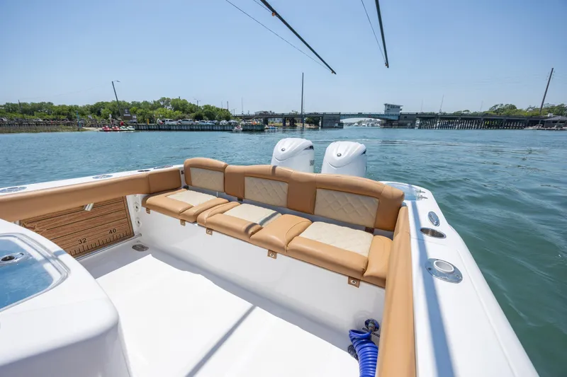 Slide: The Image of 2024 NauticStar 252 Legacy boat with tan seating, dual engines, and scenic waterfront view. - 10