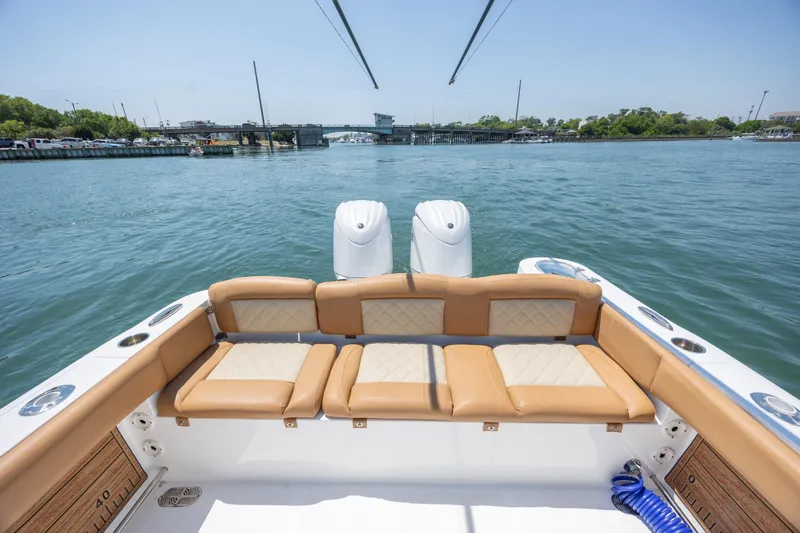 Slide: The Image of 2024 NauticStar 252 Legacy boat with tan seating, dual engines, and scenic water view. - 11