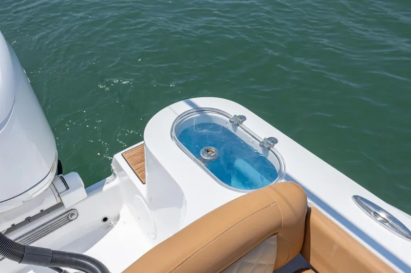 Slide: The Image of 2024 NauticStar 252 Legacy boat with livewell and tan seating on calm water. - 14