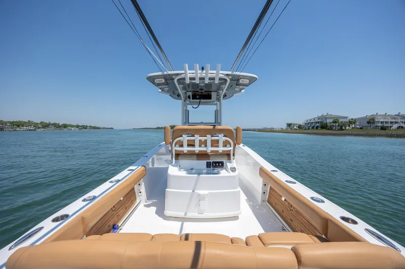 Slide: The Image of 2024 NauticStar 252 Legacy boat on calm water, featuring tan seating and modern helm. - 15