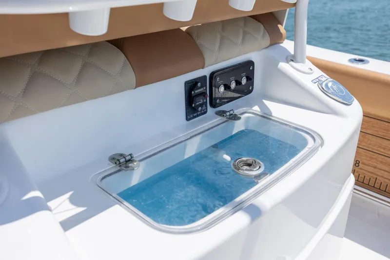 Slide: The Image of 2024 NauticStar 252 Legacy boat console with controls and livewell, featuring luxurious seating. - 18