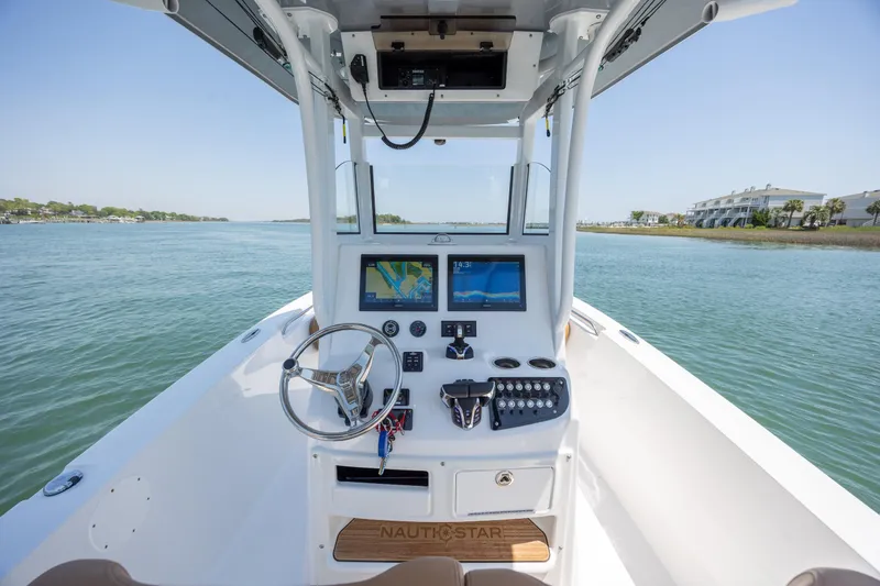 Slide: The Image of 2024 NauticStar 252 Legacy boat helm with modern navigation system on calm waters. - 19