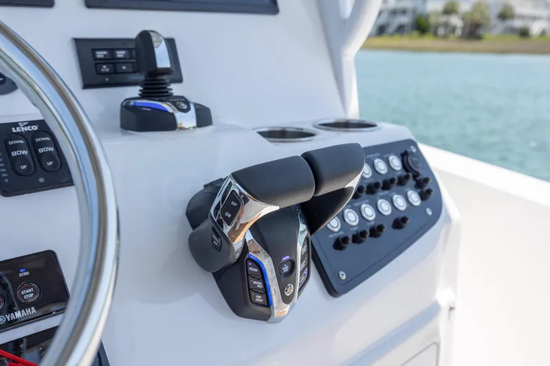 Slide: The Image of 2024 NauticStar 252 Legacy boat controls with steering wheel and throttle levers. - 24