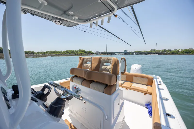 Slide: The Image of 2024 NauticStar 252 Legacy boat interior with helm and seating on calm water. - 27