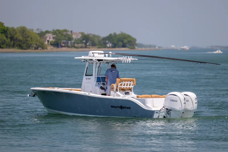 Slide: The Image of 2024 NauticStar 252 Legacy boat cruising on a calm lake with dual Yamaha engines. - 6