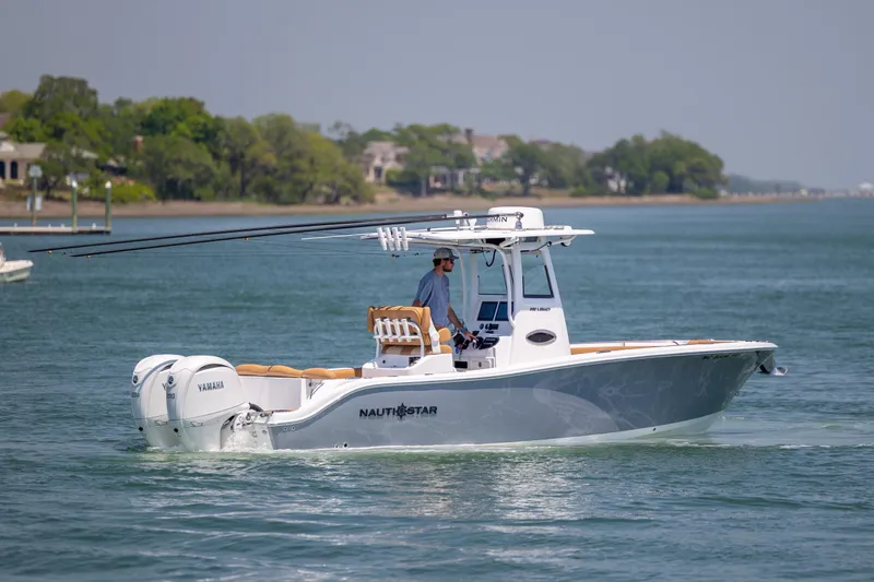 Slide: The Image of 2024 NauticStar 252 Legacy boat cruising on a serene waterway with lush greenery. - 8